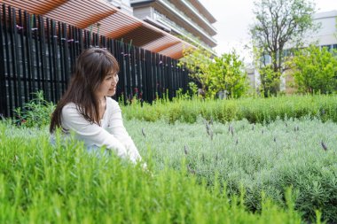 Parktaki çimlerin üzerinde oturan genç kadın. 