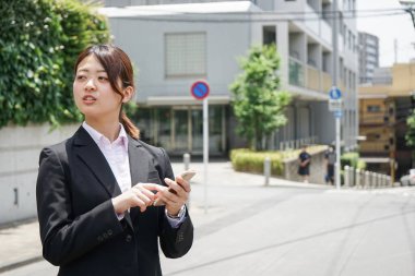 Parkta cep telefonu kullanan Asyalı iş kadınının portresi