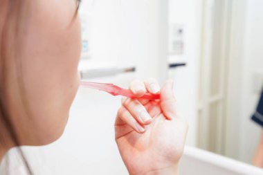 Banyoda dişlerini fırçalayan kadının elini kapat.