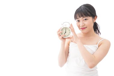 Alarmlı saati olan genç Asyalı kadın beyaz arka planda izole edilmiş.