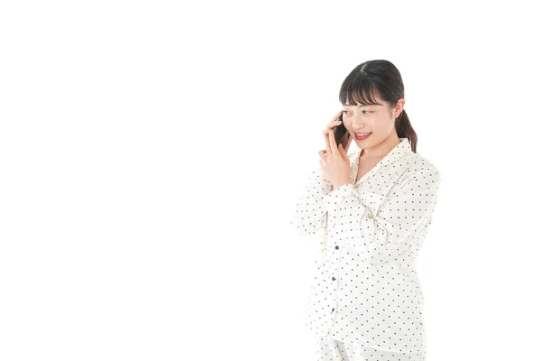 白い背景に隔離された電話で話すパジャマ姿のアジア系の若い女性 — ストック写真