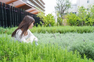 Parktaki çimlerin üzerinde oturan genç kadın. 