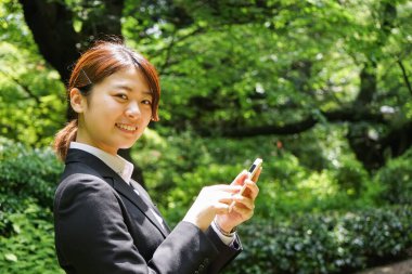 Parkta cep telefonu kullanan Asyalı iş kadınının portresi