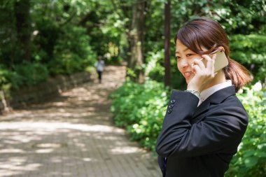 Parkta cep telefonuyla konuşan Asyalı iş kadınının portresi
