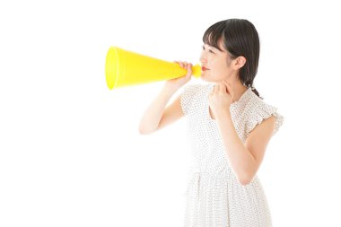 Beyaz arka planda izole edilmiş sarı megafonlu Asyalı genç kadının portresi.