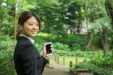 Parkta cep telefonu kullanan Asyalı iş kadınının portresi