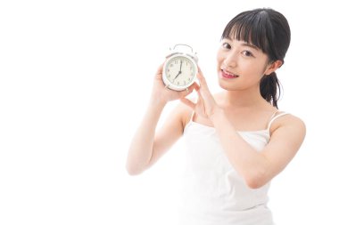 Alarmlı saati olan genç Asyalı kadın beyaz arka planda izole edilmiş.