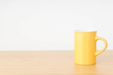 Sarı kahve fincanı ahşap masada.