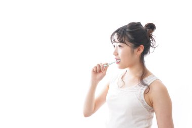 Genç Asyalı kadın evde dişlerini fırçalıyor.