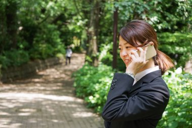Parkta cep telefonuyla konuşan Asyalı iş kadınının portresi