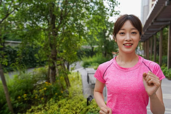 portrait of sporty Asian woman jogging in summer park