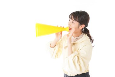 Beyaz arka planda izole edilmiş sarı megafonlu Asyalı genç kadının portresi.