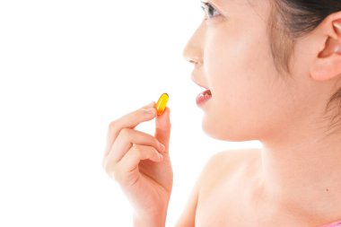 Omega-3 kapsülünü alan genç Asyalı kadın beyaz arka planda izole edilmiş.
