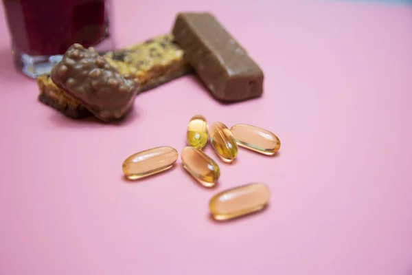 chocolate protein bar with omega 3 healthy food on a pink background.