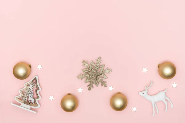 Yeni yıl ve Noel kompozisyonu. Altın toplardan, beyaz yıldızlardan, kar tanelerinden, noel ağacından, pastel pembe kağıttan arkaplandaki geyikten. Üst görünüm, düz görünüm, kopyalama alanı