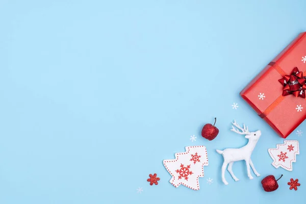 Yeni yıl ve Noel aralığı. Kırmızı ve beyaz noel süslemeleri. Hediye kutusu, yıldızlar, Noel ağacı, pastel mavi kağıtta geyik. Üst görünüm, düz görünüm, kopyalama alanı