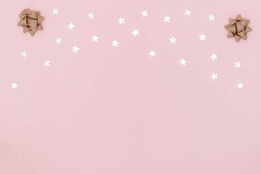 Yeni yıl, Noel aralığı, tebrik kartı. Beyaz yıldızlar, pastel pembe arka planda noel yayları. Üst görünüm, düz görünüm, kopyalama alanı