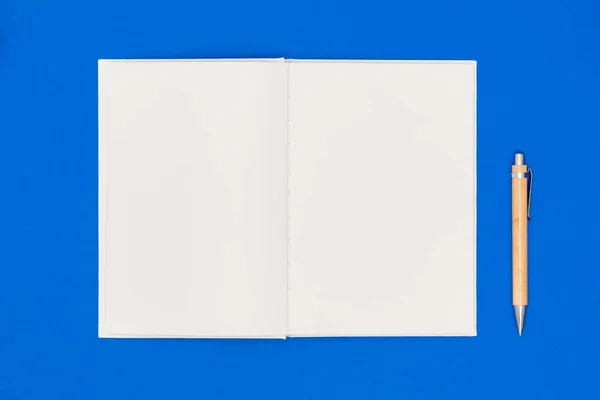Mavi arka planda defter ve kalem. Dilek listesi ya da hedef kavramı. Üst görünüm, düz görünüm, kopyalama alanı