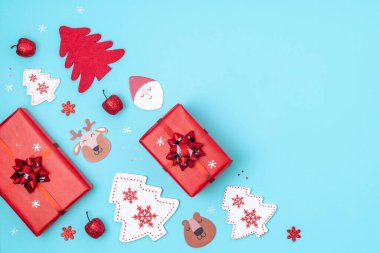 Yeni yıl ve Noel aralığı. Kırmızı ve beyaz Noel süslemeleri. Hediye kutuları, yıldızlar, Noel ağacı, pastel mavisi arka planda Noel Baba. Üst görünüm, düz görünüm, kopyalama alanı