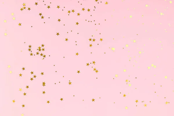 Golden stars glitter confetti on pink background. Festive backdrop. — ストック写真