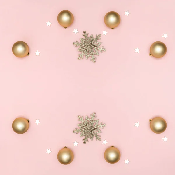 Neujahrs- und Weihnachtskomposition. Rahmen aus goldenen Kugeln, weißen Sternen, Schneeflocke auf pastellrosa Hintergrund. Draufsicht, flache Lage, Kopierraum — Stockfoto