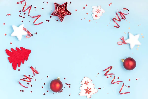 Nový rok a vánoční kompozice. Rámeček z červených míčků, bílých hvězd, vánočních stromků a jisker na pastelově modrém pozadí. Horní pohled, plochá poloha, kopírovací prostor — Stock fotografie