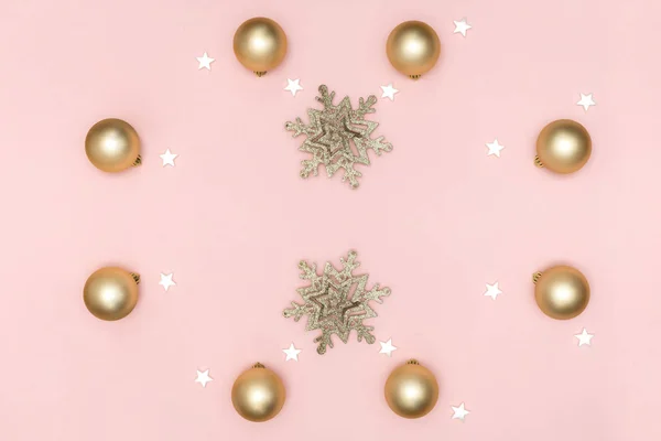 Πρωτοχρονιά και Χριστουγεννιάτικη σύνθεση. Πλαίσιο από χρυσές μπάλες, λευκά αστέρια, νιφάδες χιονιού σε παστέλ ροζ φόντο. Πάνω άποψη, επίπεδη lay, αντίγραφο χώρου — Φωτογραφία Αρχείου