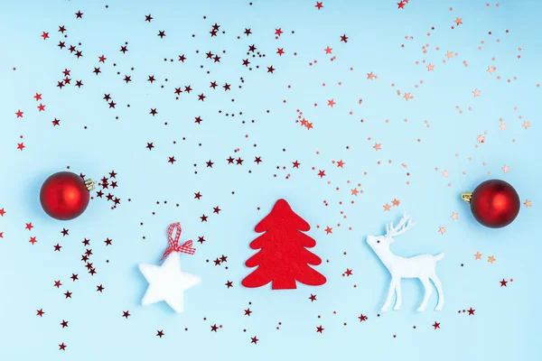 Año Nuevo y composición navideña. Marco de bolas rojas, estrellas blancas, árbol de Navidad, ciervos y destellos sobre fondo azul pastel. Vista superior, plano, espacio para copiar —  Fotos de Stock