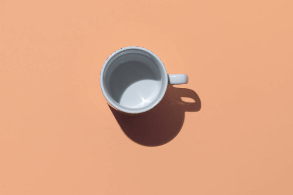 Empty tea cup on beige paper background. Coffee mug from above. Minimal concept Hard deep shadow. Flat lay, top view.