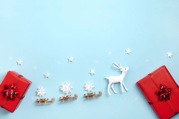 Año nuevo, marco de Navidad, tarjeta de felicitación. Estrellas blancas, ciervos con trineo de Santa Claus, cajas de regalo sobre fondo azul pastel. Vista superior, plano, espacio para copiar . —  Fotos de Stock