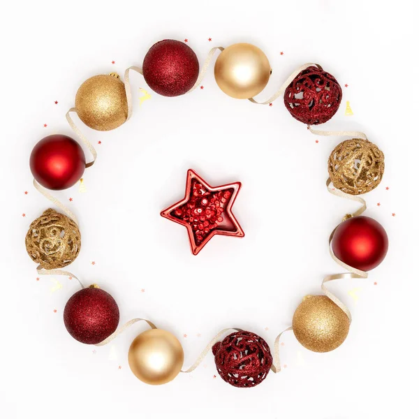 Πρωτοχρονιά και χριστουγεννιάτικη ευχετήρια κάρτα. Στεφάνι φτιαγμένο από κόκκινα και χρυσά χριστουγεννιάτικα στολίδια σε λευκό φόντο χαρτιού. Πάνω άποψη, επίπεδη lay, αντίγραφο χώρου — Φωτογραφία Αρχείου