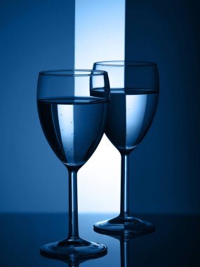 Mavi arka planda iki şarap bardağı silueti. 2020 yılının moda rengi.