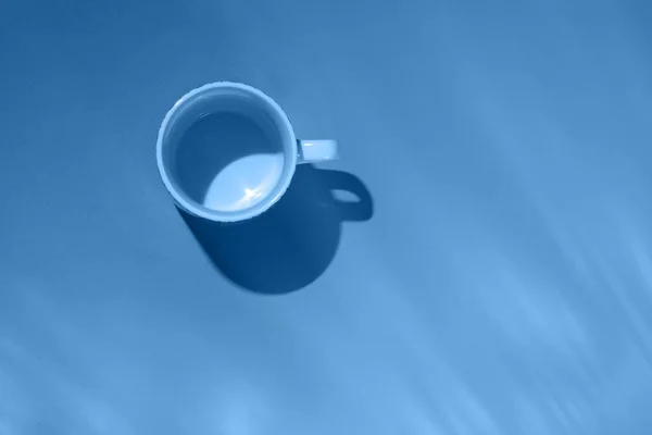 Tazza da tè vuota su sfondo di carta blu. Tazza di caffè dall'alto. Colore alla moda dell'anno 2020. Posa piatta, vista dall'alto . — Foto Stock