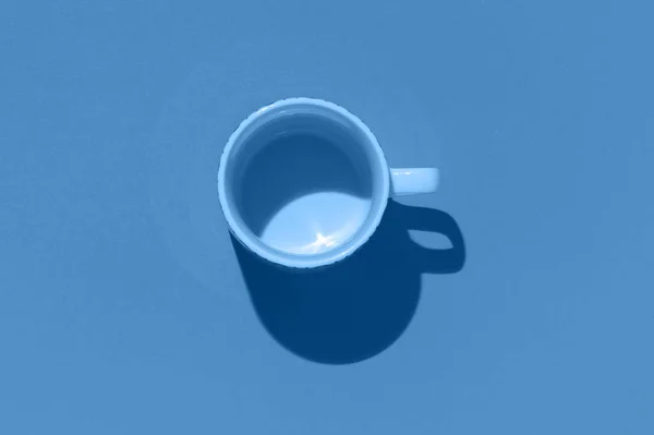 Empty tea cup on blue paper background. Coffee mug from above. Minimal concept, dark shadow. Flat lay, top view. Trendy color of the year 2020. — Stock Photo, Image