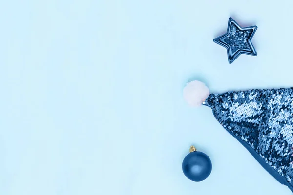 Yeni yıl ve Noel kompozisyonu. Top, yıldız, pastel mavi arka planda Noel Baba 'nın şapkası. Üst görünüm, düz görünüm, kopyalama alanı