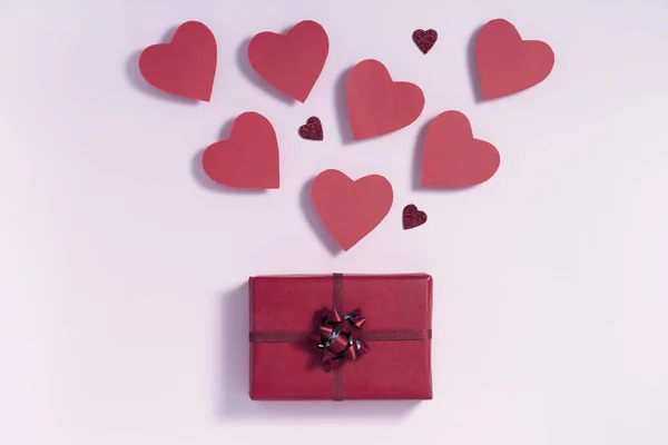 Валентинів день композиції. Бургундські серця дують з подарункової коробки на рожевому фоні. Лист від любові представляє концепцію. Вигляд зверху, зверху, зверху. — стокове фото