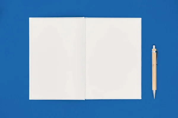 Cuaderno y pluma sobre fondo azul. Lista de deseos o concepto de metas. Vista superior, plano, espacio para copiar —  Fotos de Stock