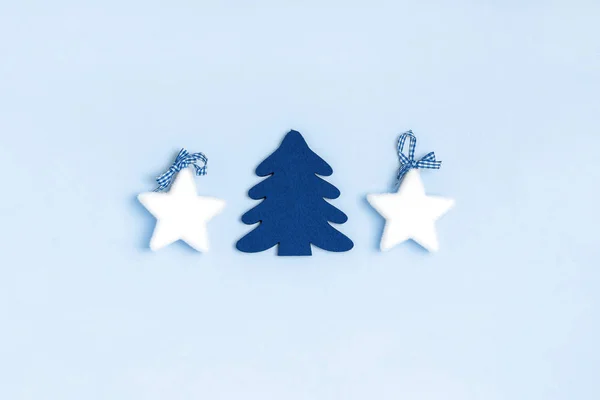 Beyaz yıldızlardan yeni yıl ve Noel kompozisyonu, pastel mavi arka planda noel ağacı. Üst görünüm, düz görünüm, kopyalama alanı