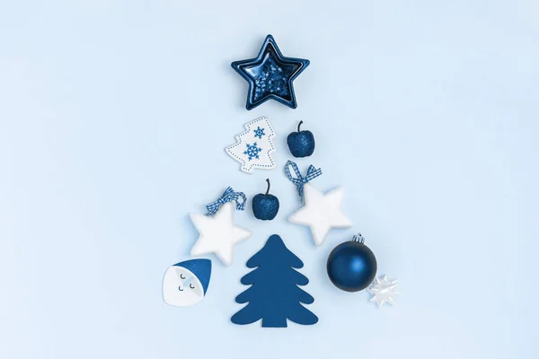 Yılbaşı ve Noel kompozisyonu noel ağacı şeklinde. Yıldızlar, noel baloları, mavi arka planda oyuncaklar. Üst görünüm, düz görünüm, kopyalama alanı. 2020 yılının moda rengi.
