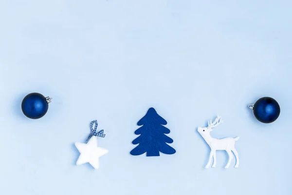 Nový rok a vánoční kompozice. Rámeček z modrých koulí, bílé hvězdy, vánoční stromeček, jelen na modrém pozadí. Horní pohled, plochá poloha, kopírovací prostor — Stock fotografie