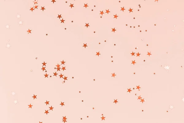 Golden stars glitter confetti on peach colored background. Festive backdrop. — Stock Photo, Image