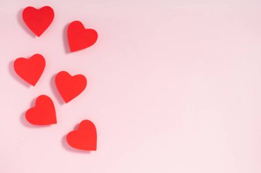 Sevgililer Günü kompozisyonu. Pastel pembe arka planda kırmızı kalpler. Üst görünüm, düz görünüm, kopyalama alanı