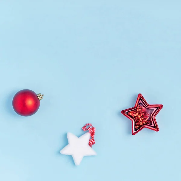 Año Nuevo y composición navideña. Juguetes de Navidad rojos y blancos: estrellas, bolas de Navidad sobre fondo de papel azul pastel. Vista superior, plano, espacio para copiar —  Fotos de Stock