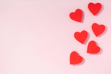 Sevgililer Günü kompozisyonu. Pastel pembe arka planda kırmızı kalpler. Üst görünüm, düz görünüm, kopyalama alanı