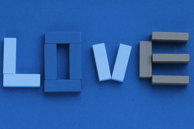 Aşk kelimesi mavi arka plandaki ahşap tuğlalardan yapılmış. Üst manzara, düz yatış. Moda rengi: 2020