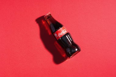 Kırmızı arka planda cam şişede Coca Cola. İtalya, Milan - 15 Kasım 2019