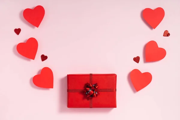 Kompozycja walentynkowa. Czerwone serca wiejące z pudełka na pastelowym różowym tle. List miłosny przedstawia koncepcję. Płaskie ułożenie, widok z góry, z góry — Zdjęcie stockowe
