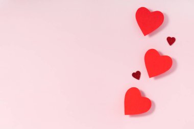 Sevgililer Günü kompozisyonu. Pastel pembe arka planda kırmızı kalpler. Üst görünüm, düz görünüm, kopyalama alanı