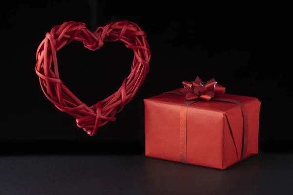 Koncepcja Walentynek. Wiklinowe lewitujące czerwone serce, pudełka prezentów na czarnym tle. Kartka okolicznościowa, pocztówka — Zdjęcie stockowe