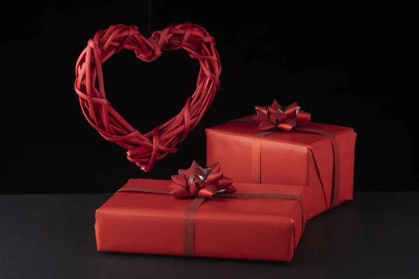 Концепция Дня Святого Валентина. Плетеные левитации красное сердце и подарочные коробки на черном фоне. Открытки, открытки — стоковое фото